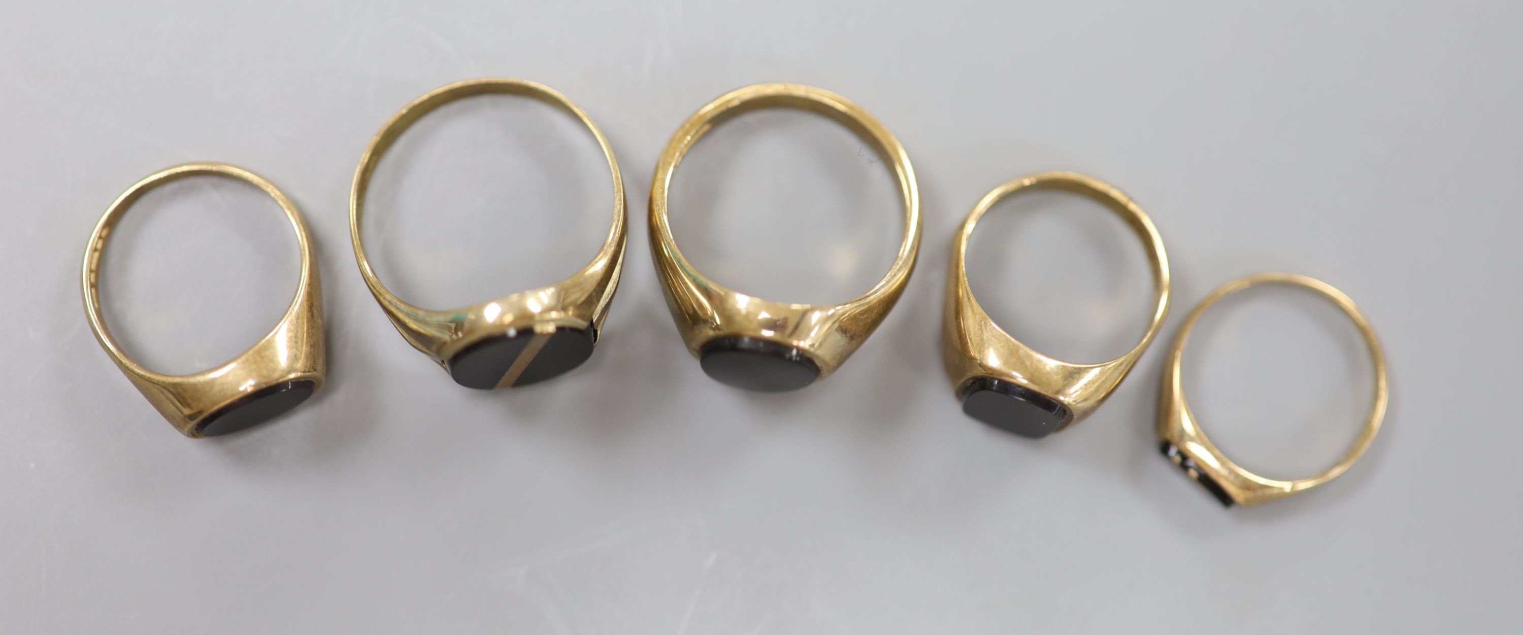 Four assorted modern 9ct gold and black onyx set signet rings and one other similar ring, largest size V/W